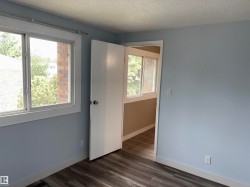 Room featuring light blue walls, white trim, and wood-finish flooring - 