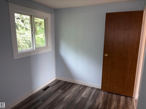 Room featuring wood-finish flooring, light blue walls, white baseboards, and a window with white trim - 167 Ridgewood, St. Albert, AB - Indoor Photo Showing Other Room