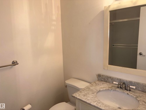 Bathroom vanity with an oval undermount sink, a polished chrome faucet with white handles, and a light-colored stone countertop - 167 Ridgewood, St. Albert, AB - Indoor Photo Showing Bathroom