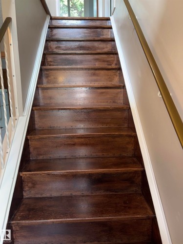 Wood-finish staircase featuring a brass handrail, white balusters, and a neutral wall color - 167 Ridgewood, St. Albert, AB - Indoor Photo Showing Other Room
