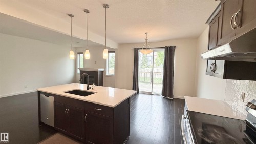 Kitchen island featuring a dark finish, integrated sink, and white countertop - 3962 Claxton Loop, Edmonton, AB - Indoor Photo Showing Kitchen
