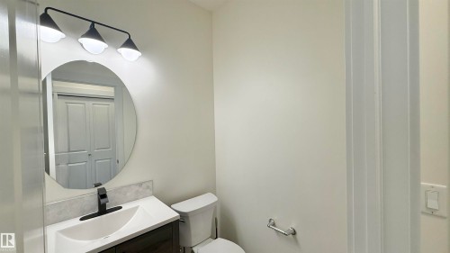 Bathroom featuring a white vanity with an integrated sink, a dark wood-finish cabinet, and a black faucet - 3962 Claxton Loop, Edmonton, AB - Indoor Photo Showing Bathroom