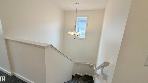 Stairwell featuring a contemporary chandelier, white window trim, and neutral wall tones - 3962 Claxton Loop, Edmonton, AB - Indoor Photo Showing Other Room
