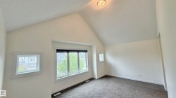 Vaulted ceilings enhance this room, featuring recessed lighting, a large picture window, and additional windows with white trim - 