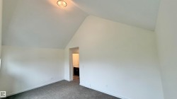 Vaulted ceiling room featuring neutral-toned walls, gray carpet flooring, and a flush-mount ceiling light fixture - 