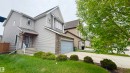 Contemporary facade featuring light grey horizontal siding, a stone accent garage, a prominent gable, a covered entryway with a blue door, and a concrete driveway - 3962 Claxton Loop, Edmonton, AB  - Outdoor 