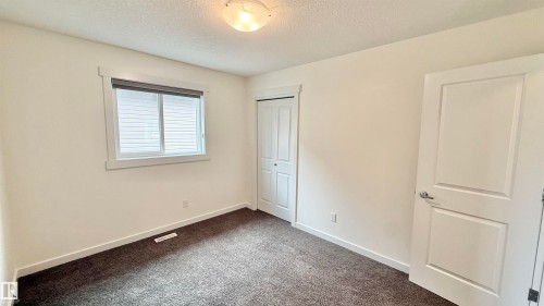 Neutral wall paint and dark carpet flooring create a versatile interior - 3962 Claxton Loop, Edmonton, AB - Indoor Photo Showing Other Room