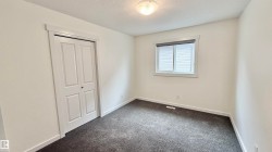 Bright room featuring neutral wall tones, dark textured carpeting, a double bifold closet, and a window with blinds - 