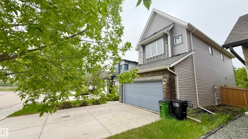 Contemporary two-story exterior featuring a single-car garage with an overhead door, stone veneer accents, and horizontal siding - 3962 Claxton Loop, Edmonton, AB - Outdoor