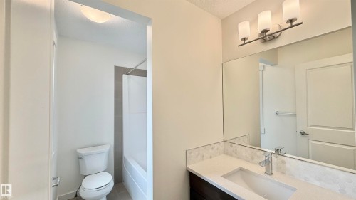 Bathroom vanity featuring a rectangular undermount sink, a chrome single-handle faucet, and a light-toned countertop - 3962 Claxton Loop, Edmonton, AB - Indoor Photo Showing Bathroom