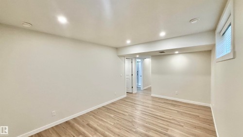 Spacious room featuring wood-finish flooring, recessed ceiling lighting, a window with horizontal blinds, and a white interior door - 3962 Claxton Loop, Edmonton, AB - Indoor Photo Showing Other Room