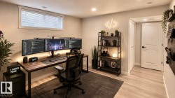 Dedicated workspace featuring wood-finish flooring, recessed lighting, and a modern desk setup - 