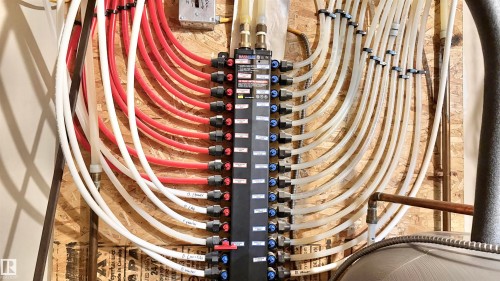 Radiant heating manifold system featuring multiple PEX lines, a central distribution panel, and integrated shut-off valves - 3962 Claxton Loop, Edmonton, AB - Indoor