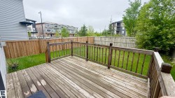 Spacious outdoor deck with wood railings overlooking a fenced backyard - 