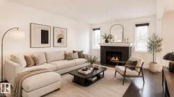 Spacious living area featuring dark wood-finish flooring, a contemporary fireplace with dark tile surround and a white mantel, and multiple windows providing natural illumination - 