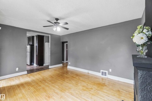 Open concept living area featuring wood-finish flooring, a ceiling fan with integrated lighting, and neutral wall tones - 11842 93 Street, Edmonton, AB 