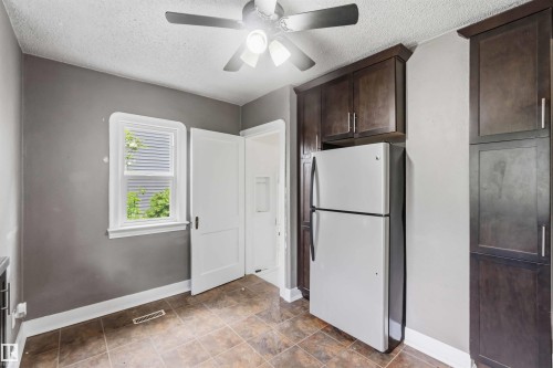Kitchen featuring dark wood-finish cabinetry, tile flooring, and a ceiling fan with integrated lighting - 11842 93 Street, Edmonton, AB 
