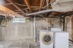 Utility area featuring exposed wood ceiling joists, a small casement window, and a concrete floor - 