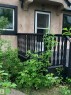 Exterior featuring a neutral-toned stucco finish, black trim accents, and a contrasting white storm door - 11842 93 Street, Edmonton, AB 