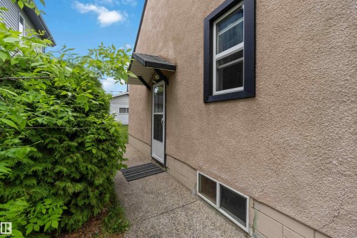 Stucco exterior featuring a side entrance with an awning - 11842 93 Street, Edmonton, AB 