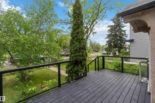 Outdoor deck featuring dark wood-finish flooring, black metal railings, and clear glass panels - 11842 93 Street, Edmonton, AB 