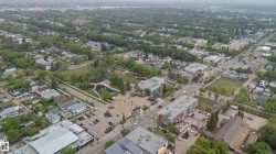 Aerial perspective showcasing a mixed-use neighborhood with mature tree-lined streets, residential properties, commercial buildings, and dedicated green spaces - 