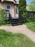 Entry porch with dark railing and stairs, featuring a light-colored stucco facade and white-framed windows - 11842 93 Street, Edmonton, AB 