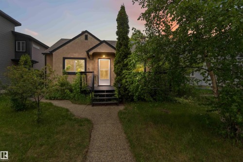 Stucco exterior with dark trim, featuring a front porch with stairs - 11842 93 Street, Edmonton, AB 