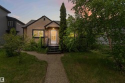 Stucco exterior with dark trim, featuring a front porch with stairs - 