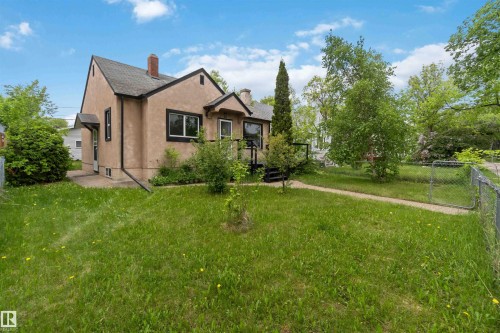 Stucco exterior residence with a shingled roof, featuring a front porch entry and dark trim windows - 11842 93 Street, Edmonton, AB 