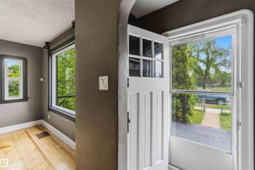 Entryway featuring a white paneled door with glass inserts, a white storm door, and a front porch - 11842 93 Street, Edmonton, AB 