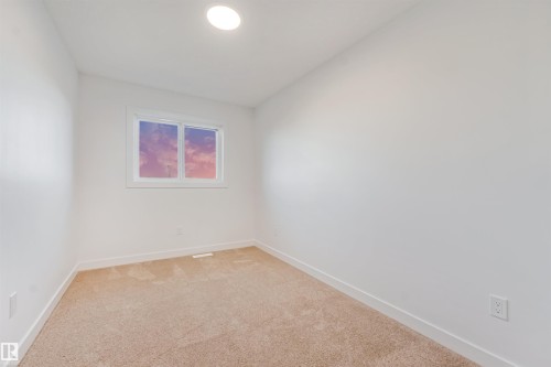 Recessed ceiling lighting illuminates a room featuring a double-paned window, neutral carpeting, and white walls - 1511 211 Street Nw, Edmonton, AB 