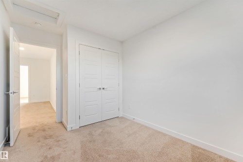 Neutral tone wall paint, light-colored carpeting, white paneled bifold closet doors, white paneled interior door - 1511 211 Street Nw, Edmonton, AB 