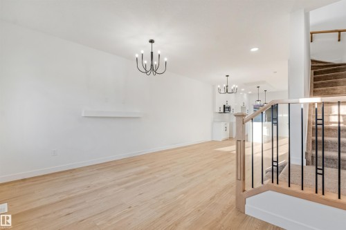 Spacious room with wood-finish flooring and a contemporary chandelier - 1511 211 Street Nw, Edmonton, AB 