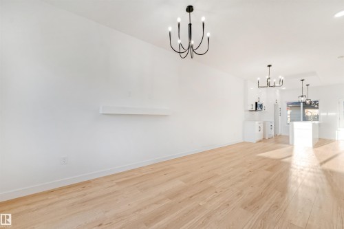 Light wood-finish flooring, white walls, modern black chandeliers, and a built-in wall shelf - 1511 211 Street Nw, Edmonton, AB 