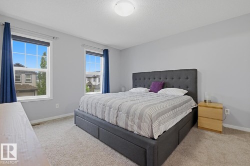 Spacious room featuring light gray walls, textured carpet flooring, and two large windows - 17844 61 Street, Edmonton, AB 