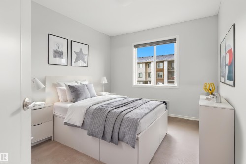 Bedroom featuring a large window with white trim, light gray walls, and carpeting - 17844 61 Street, Edmonton, AB 
