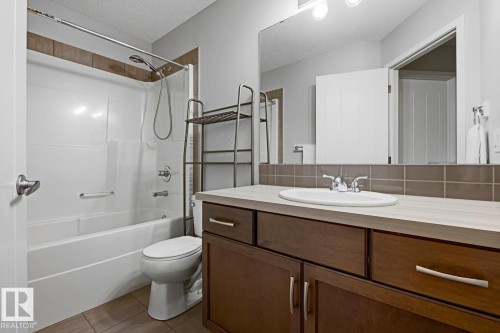 Bathroom featuring a dark wood-finish vanity with a light countertop, an oval undermount sink, and a large wall-mounted mirror - 17844 61 Street, Edmonton, AB 