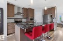 Kitchen featuring a central island with a sink, stainless steel appliances, wood-finish flooring, recessed lighting, and pendant lighting - 17844 61 Street, Edmonton, AB 