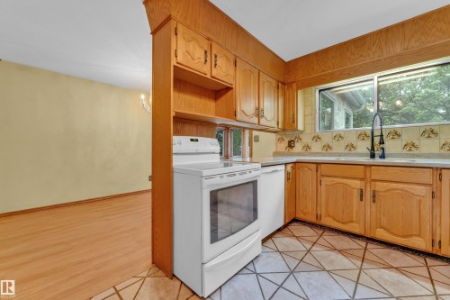 Kitchen featuring wood cabinetry, integrated white appliances, and a tiled backsplash - 10819 54 Avenue, Edmonton, AB 
