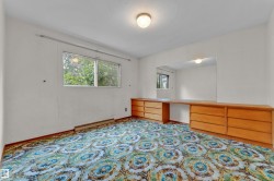 Room featuring a window with exterior foliage, patterned carpet flooring, and a built-in wood-finish vanity with drawer storage - 