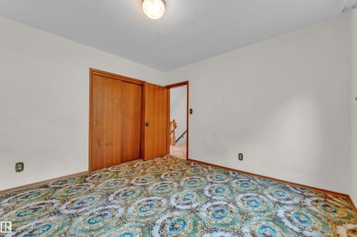 Interior room featuring patterned carpet, light-colored walls, and a wooden bi-fold closet door - 10819 54 Avenue, Edmonton, AB 