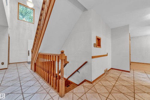 Two-story entryway featuring a light wood staircase, a large overhead window, and a chandelier - 10819 54 Avenue, Edmonton, AB 
