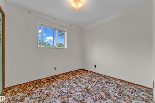 Bright interior space featuring a multi-pane window, white walls, and a patterned carpet - 10819 54 Avenue, Edmonton, AB 