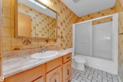 Bathroom featuring a wood vanity with an integrated sink, a large mirrored medicine cabinet, a full bathtub with sliding glass doors, and a tiled floor - 