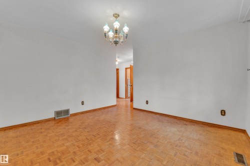 Room featuring parquet wood flooring and white walls - 10819 54 Avenue, Edmonton, AB 