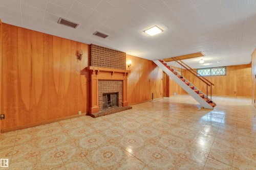 Spacious room featuring wood paneling, patterned floor tiles, and a brick fireplace with a wood mantle - 10819 54 Avenue, Edmonton, AB 