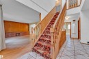 Entry foyer featuring geometric floor tiling, a wooden staircase with patterned runner, and a double-height ceiling - 10819 54 Avenue, Edmonton, AB 
