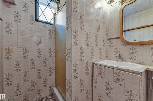 Bathroom featuring floral-patterned wall tiles and a white ceramic sink - 10819 54 Avenue, Edmonton, AB 