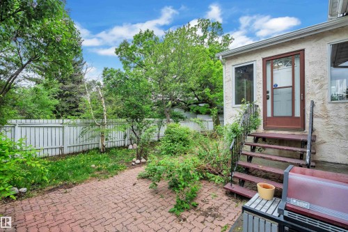 Exterior patio area featuring red brick pavers and a wooden staircase providing access to the property - 10819 54 Avenue, Edmonton, AB 
